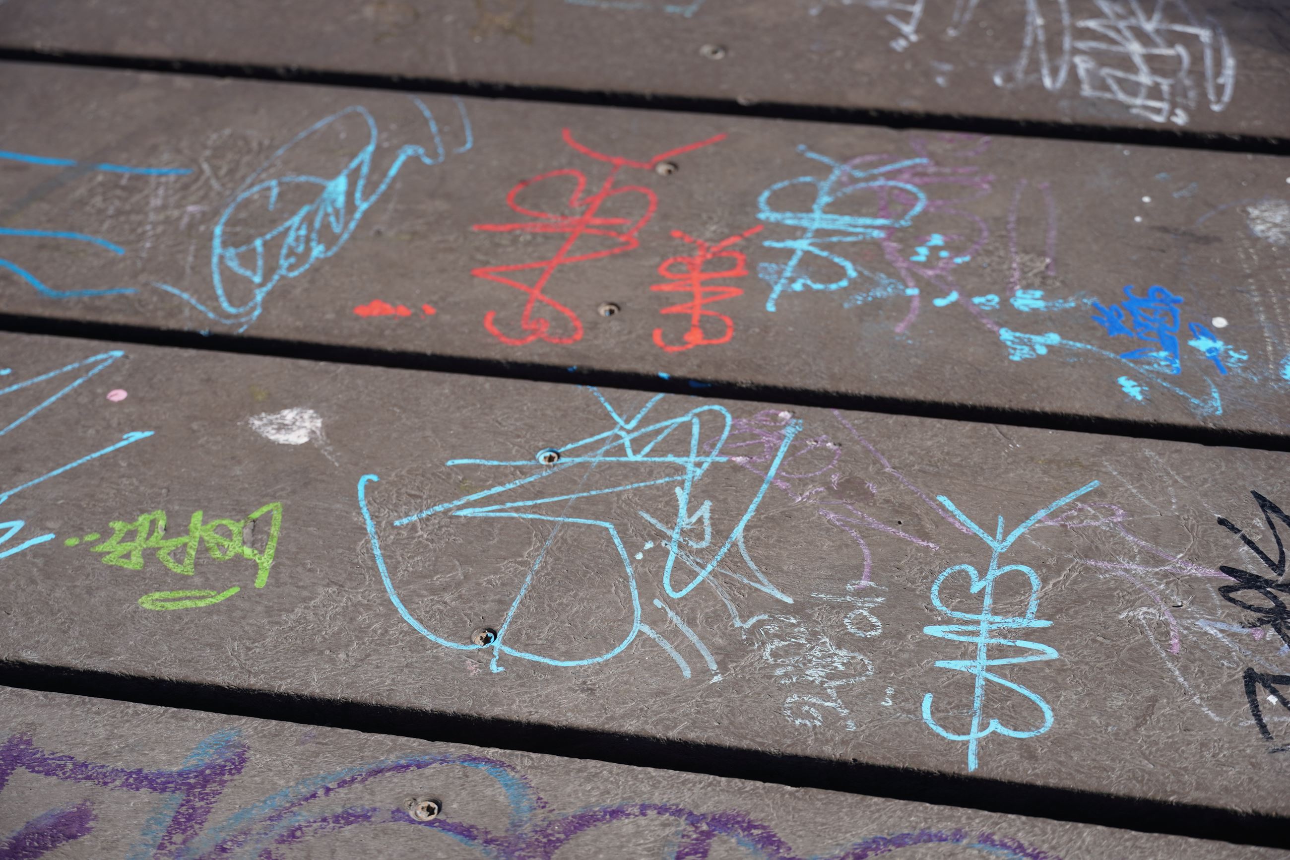 Various graffiti scribbled on sidewalk.