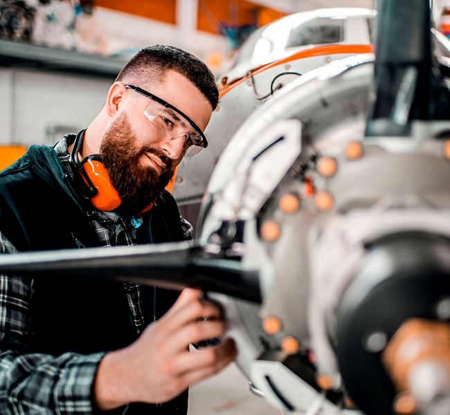 An aerospace worker inspecting the mechanics of a craft.