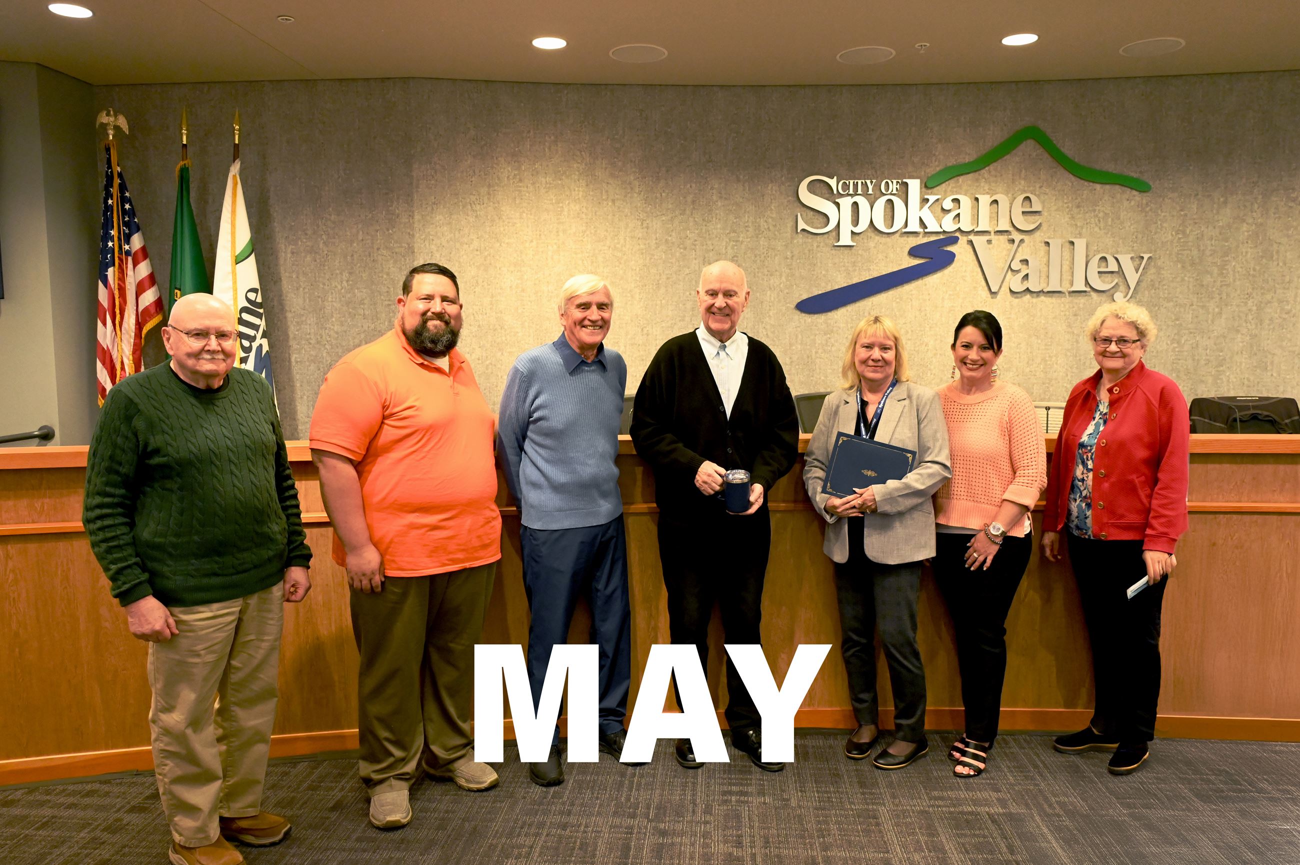 Tom Towey accepting the You Rock! award in the council chambers surrounded by councilmembers.